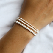 Close-up of a wrist wearing three Brea Bracelets in small, medium, and large pearl sizes, stacked for a layered look.