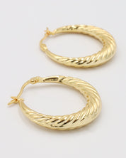 A pair of gold-colored hoop earrings with a latch back clasp on a white background.