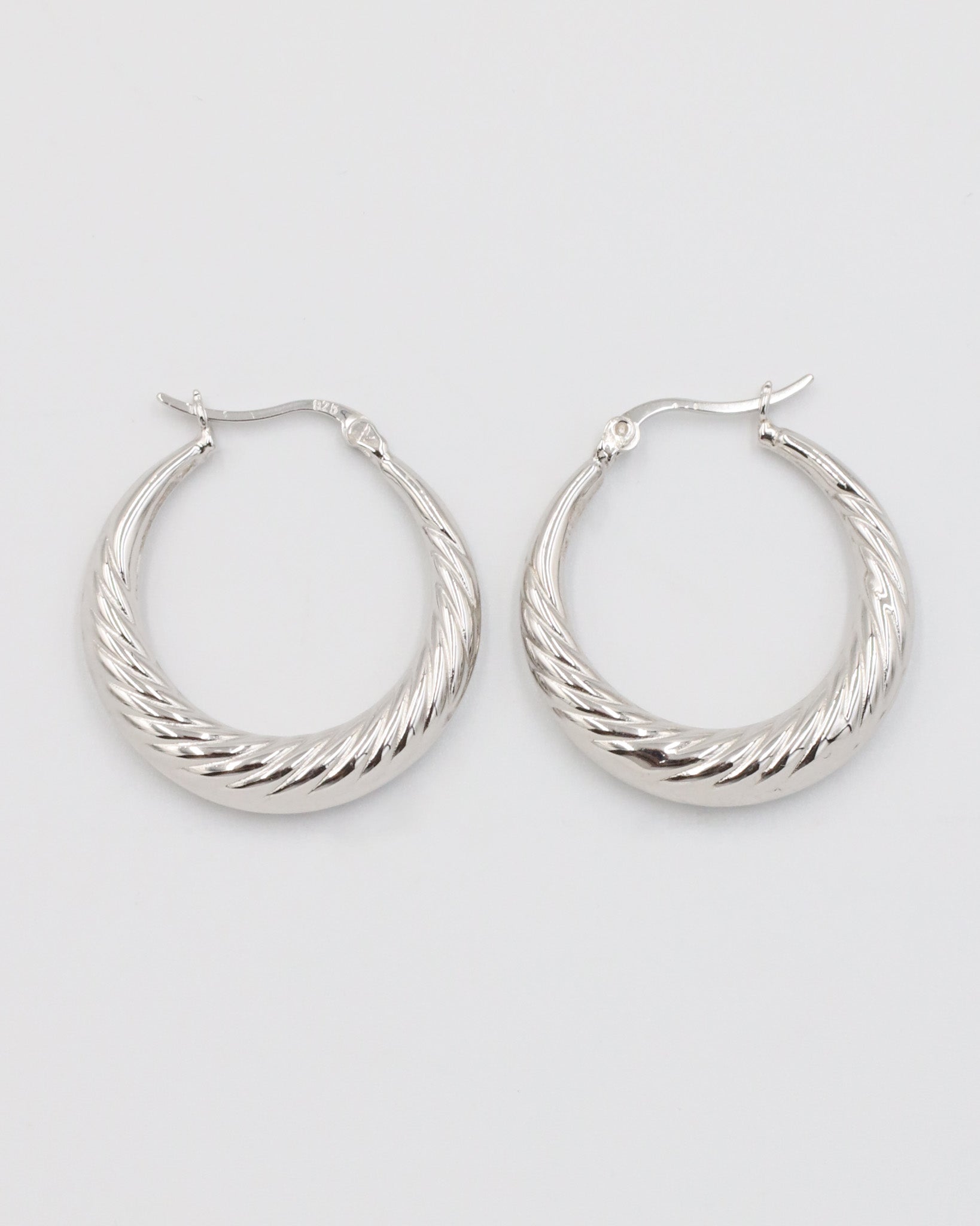 A pair of silver-colored hoop earrings with a latch back clasp.
