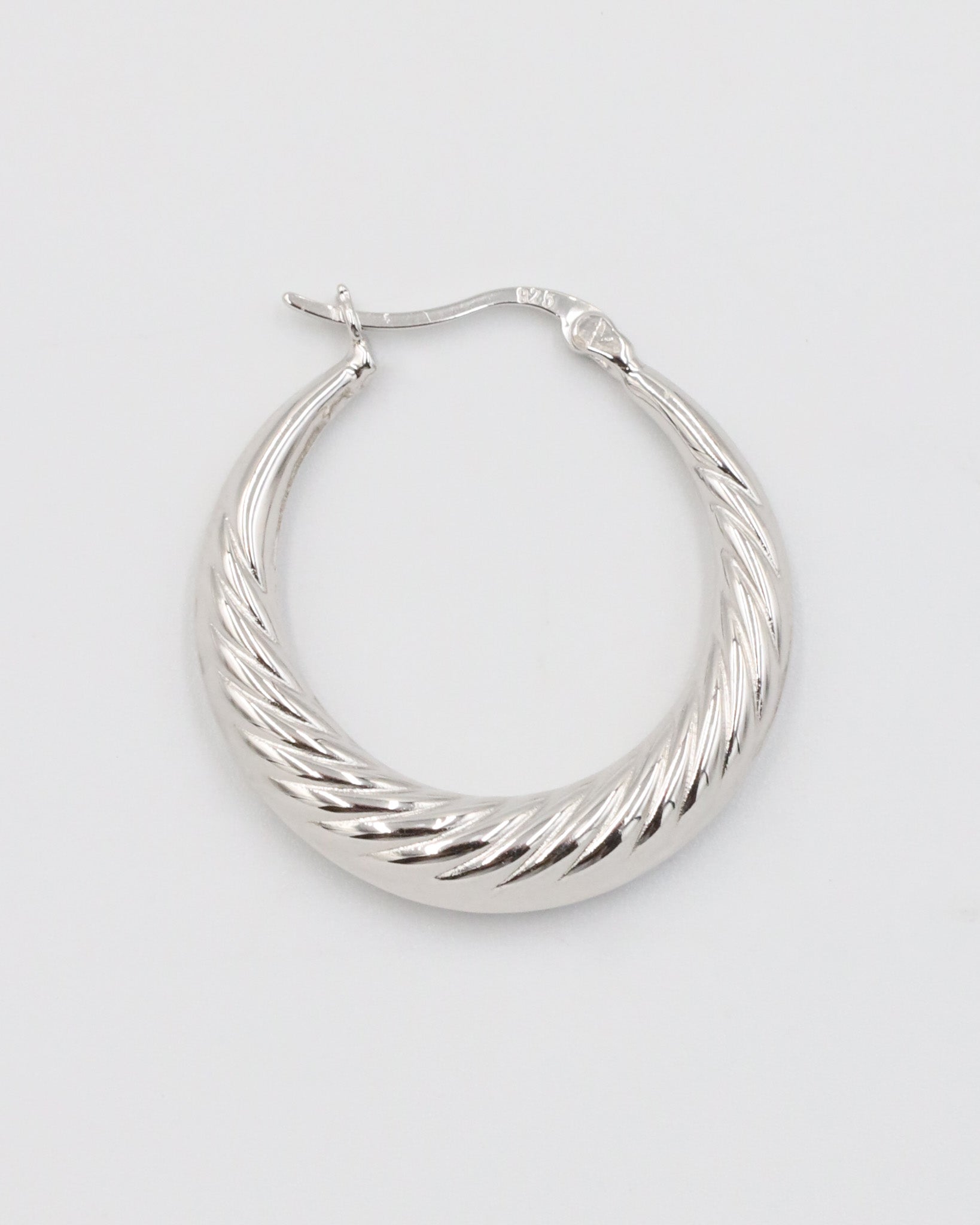 A single silver-colored hoop earring with a latch back clasp.