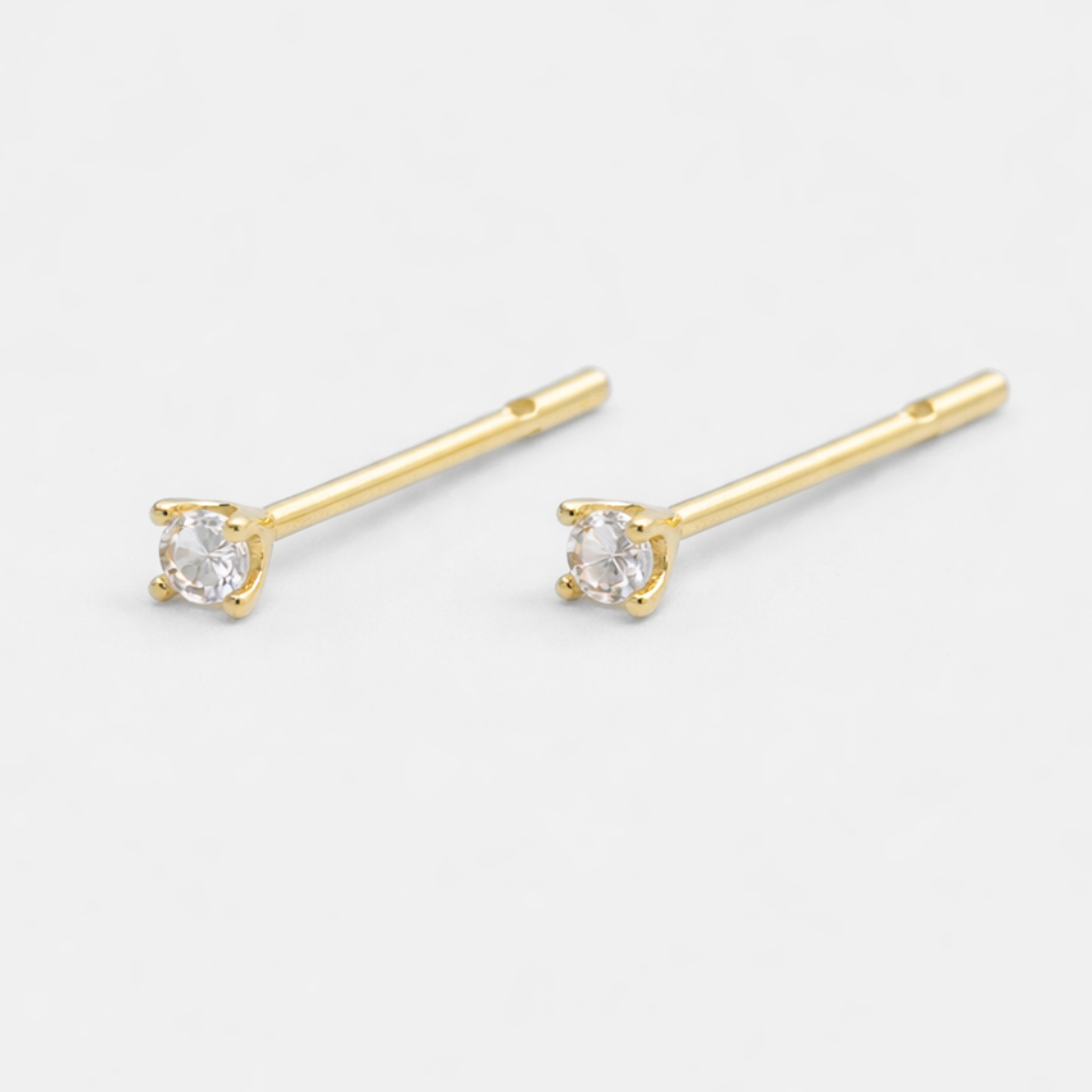 Gold stud earrings with clear gemstones on a white background