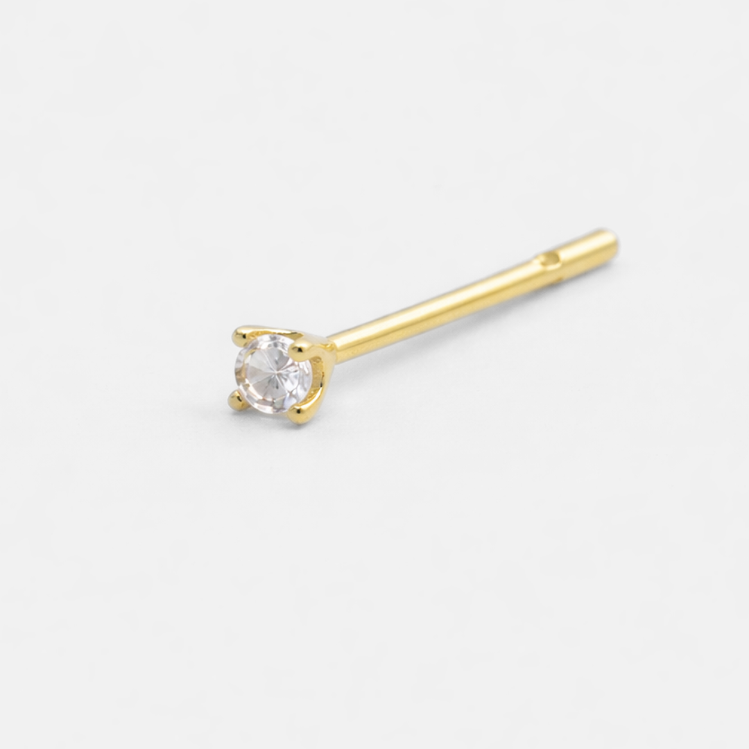 Gold stud earring with a clear gemstone on a white background