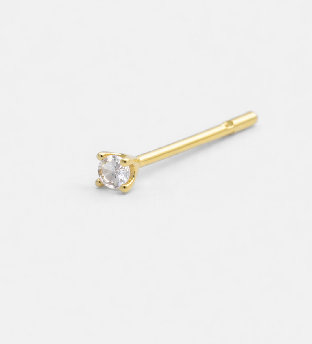 Gold stud earring with a clear gemstone on a white background