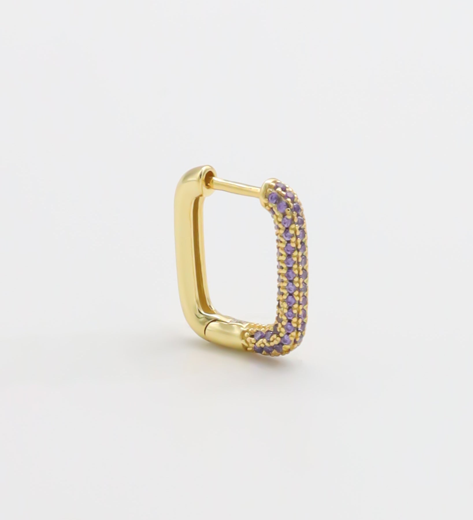 A single gold-colored hoop earring with purple accents, presented against a white background.