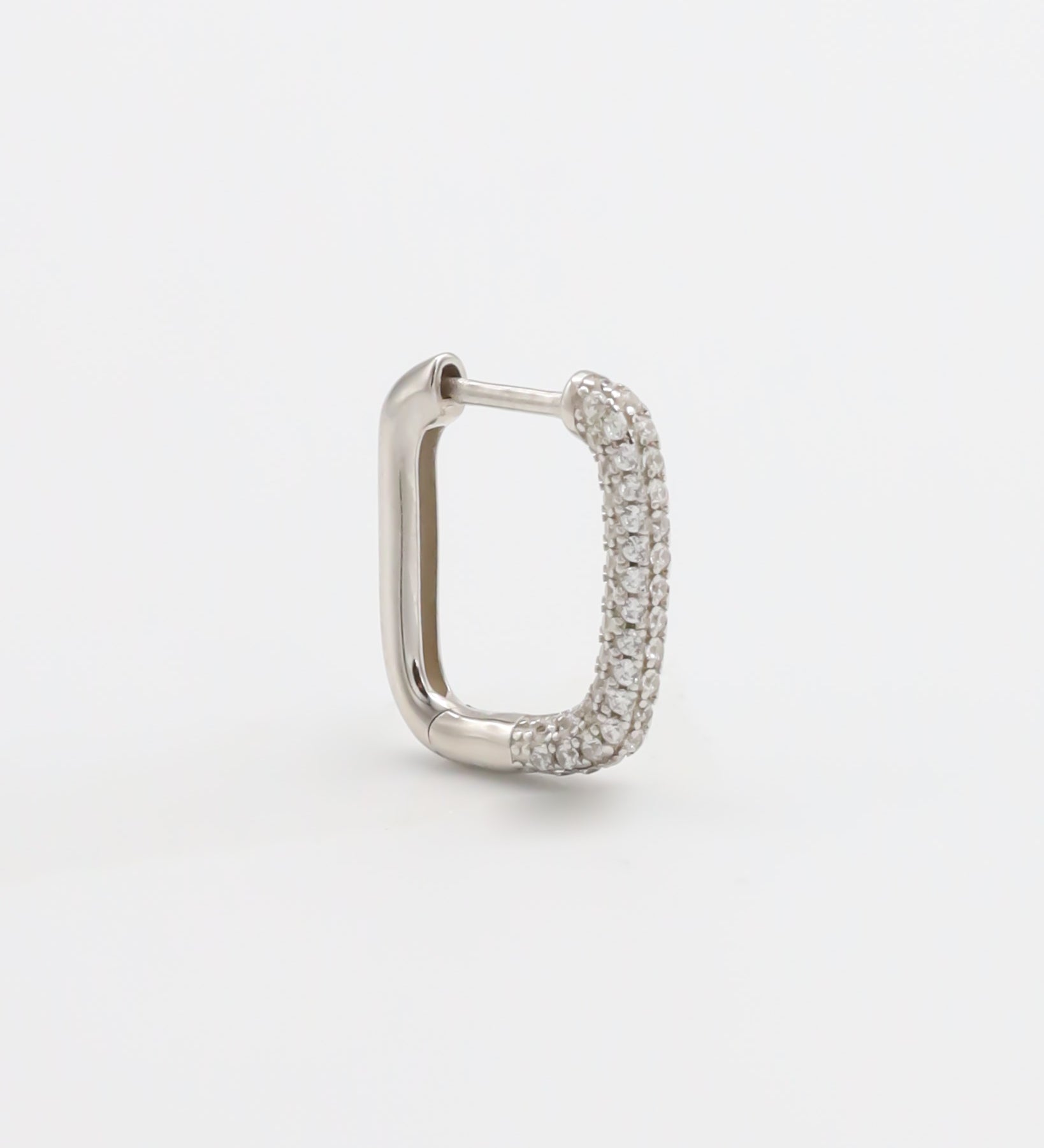 A silver hoop earring with a hinged clasp, featuring a row of small, embedded stones around the hoop.