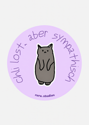 A circular sticker or decal with a light purple background, featuring a cartoon gray cat in the center and handwritten text reading 'chli lost, aber sympathisch' around the edge, with 'ruru.studios' at the bottom.