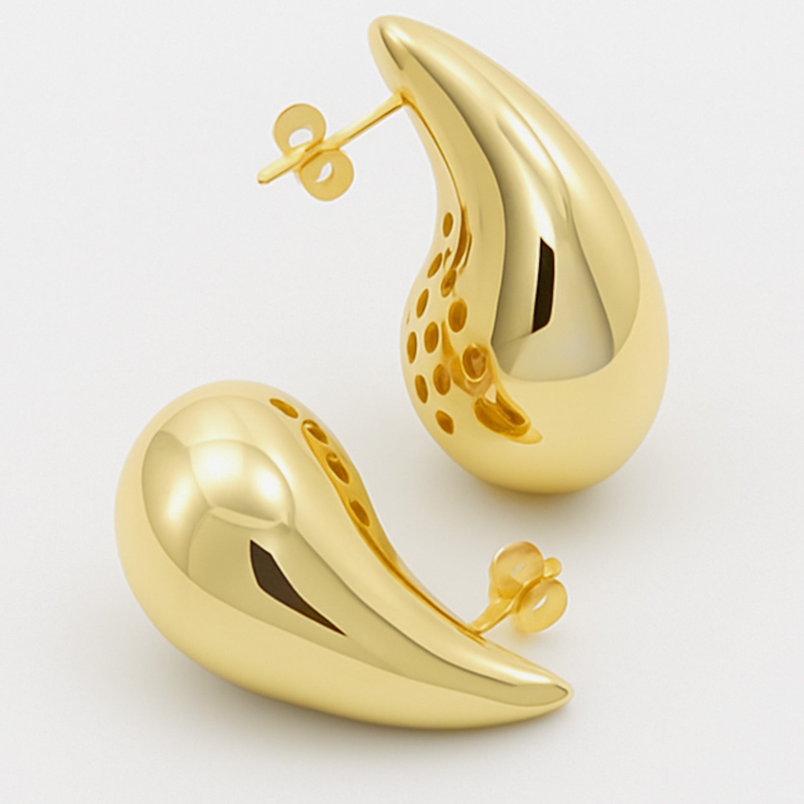 Gold earrings on a light gray background