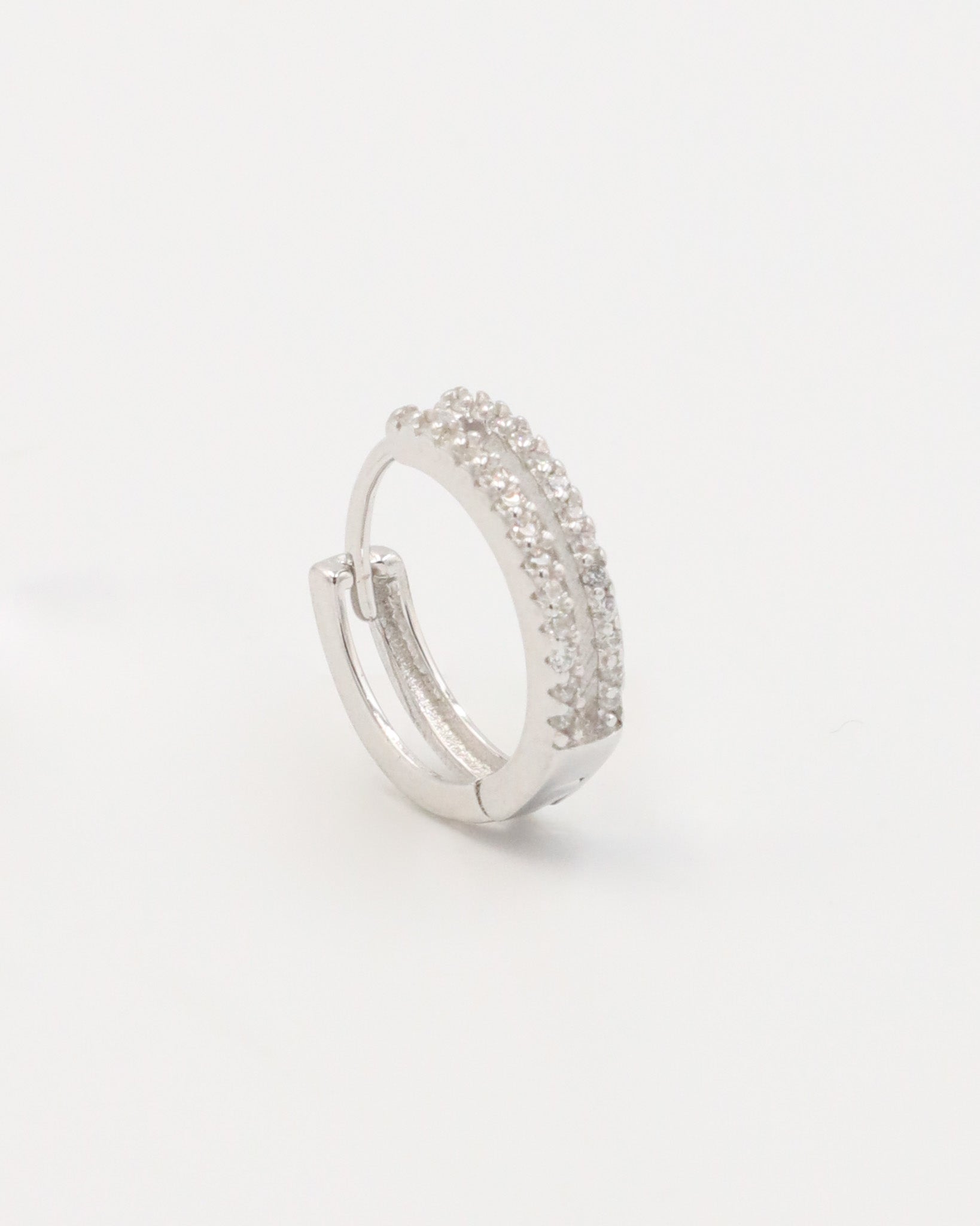 A pair of silver hoop earrings with a hinged clasp and small clear stones embedded around the hoop.