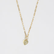 A gold-colored necklace with a heart-shaped pendant on a chain.