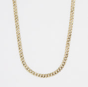 A gold-colored necklace with a curb chain link on a white background.