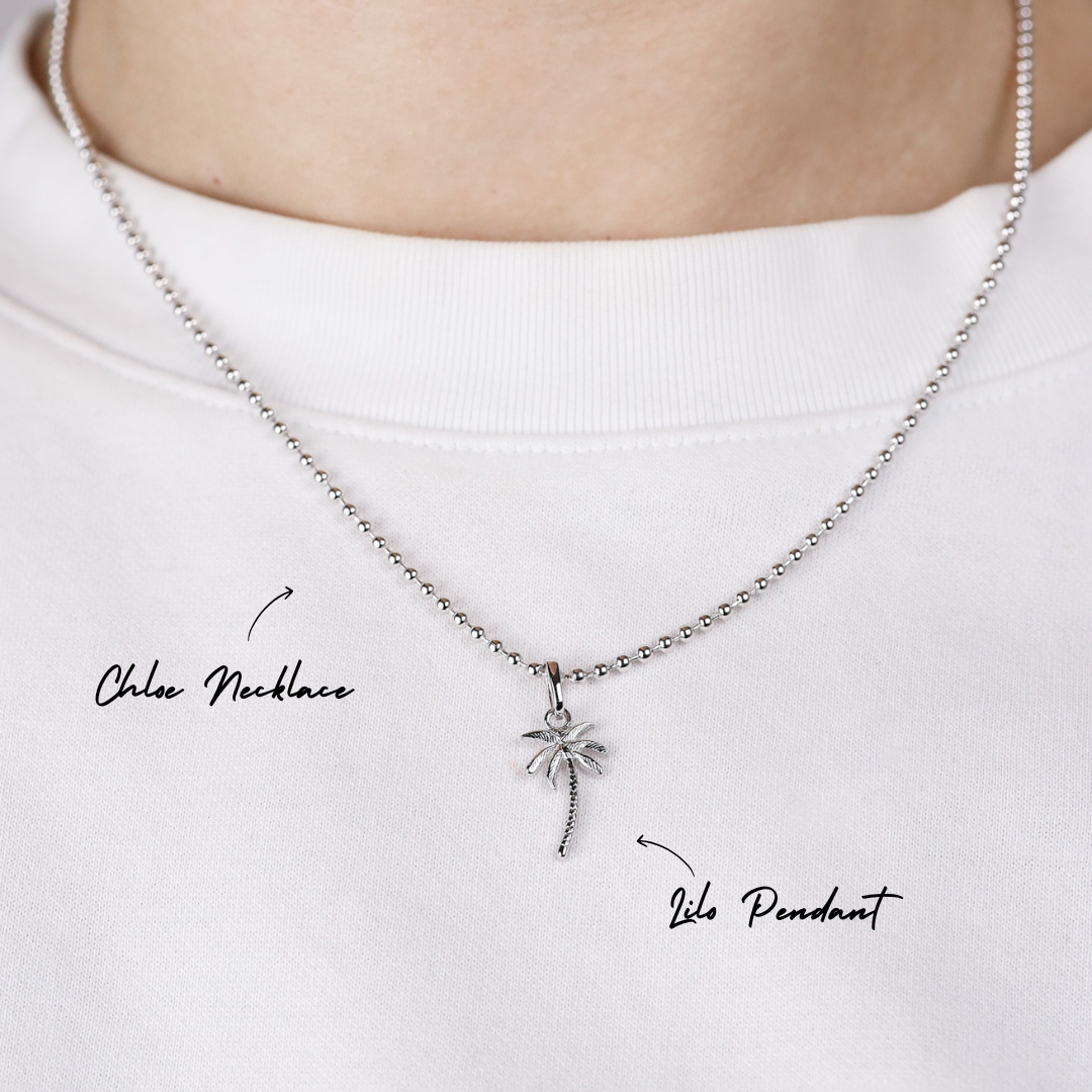 Silver necklace with a palm tree pendant on a white background