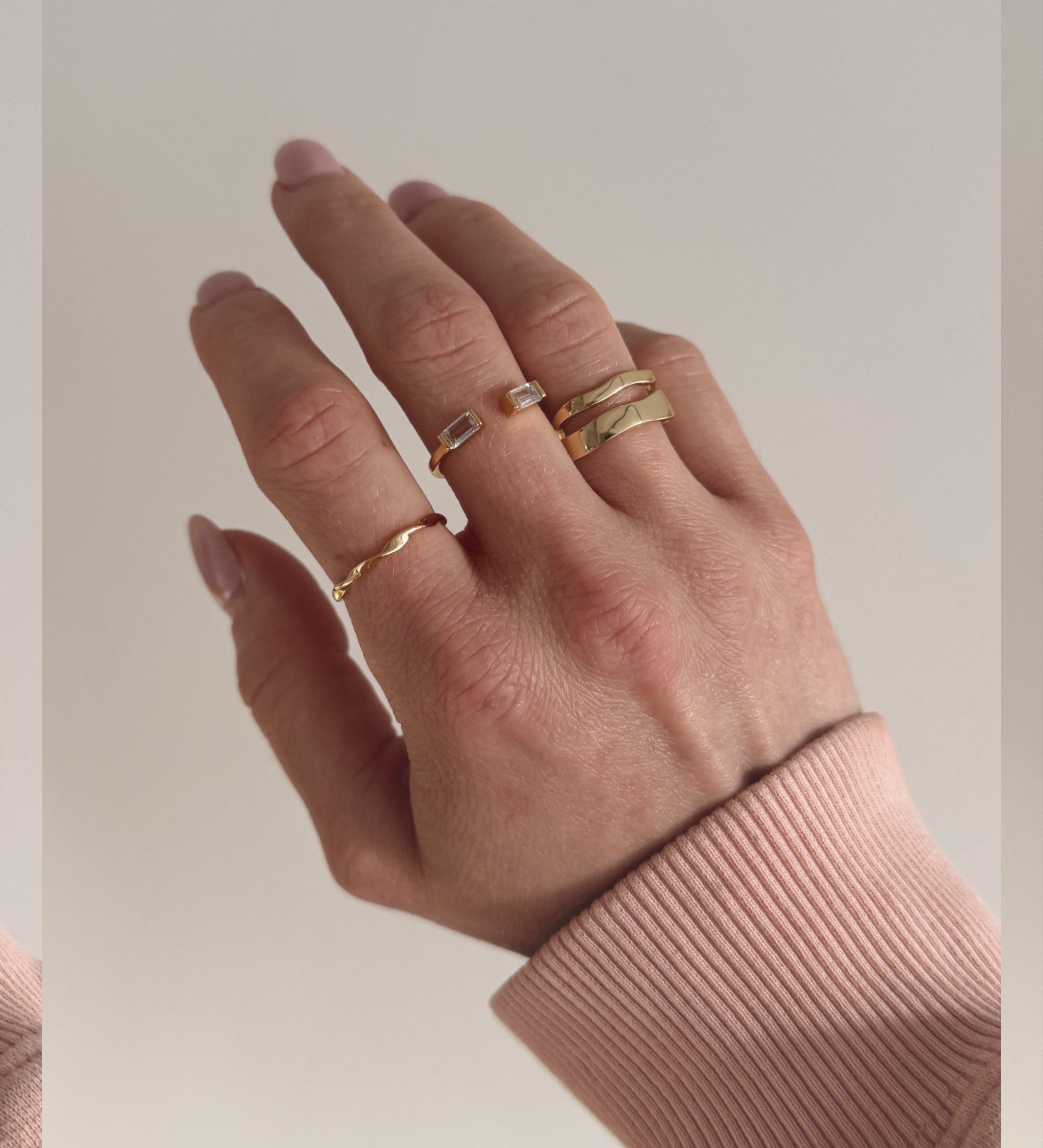 A single gold-colored ring with a smooth, curved design worn on a hand.