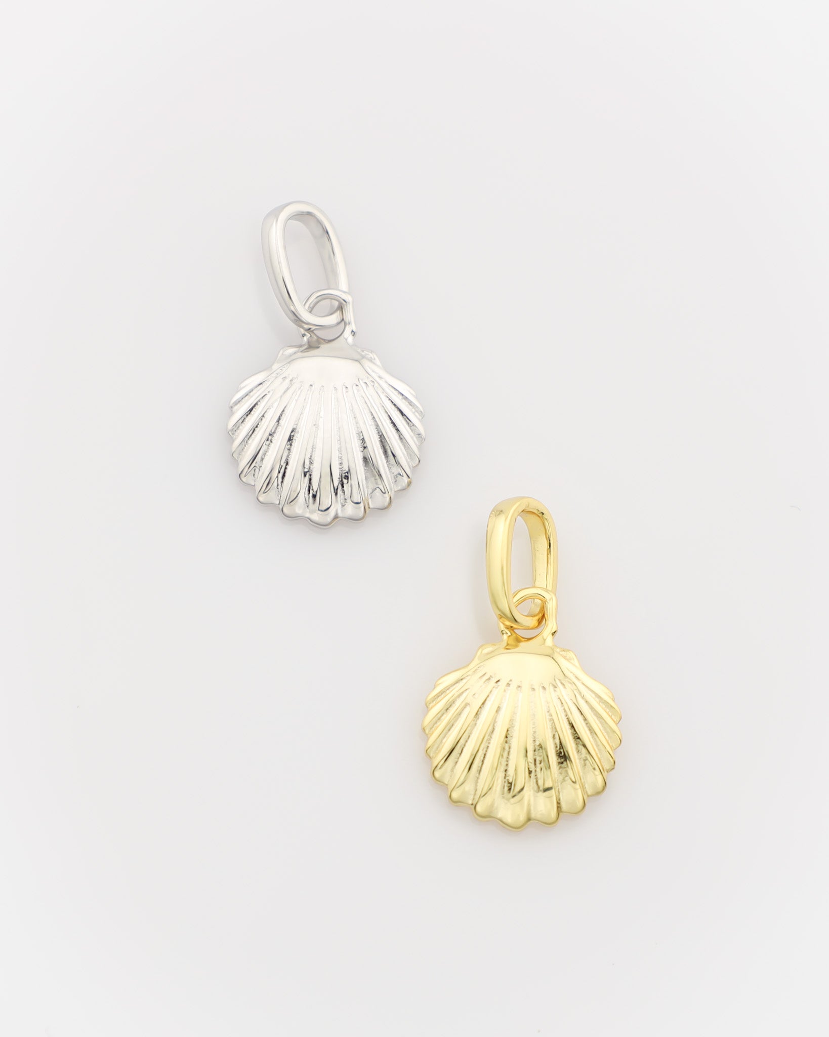 Silver and gold shell-shaped pendants on a light gray background