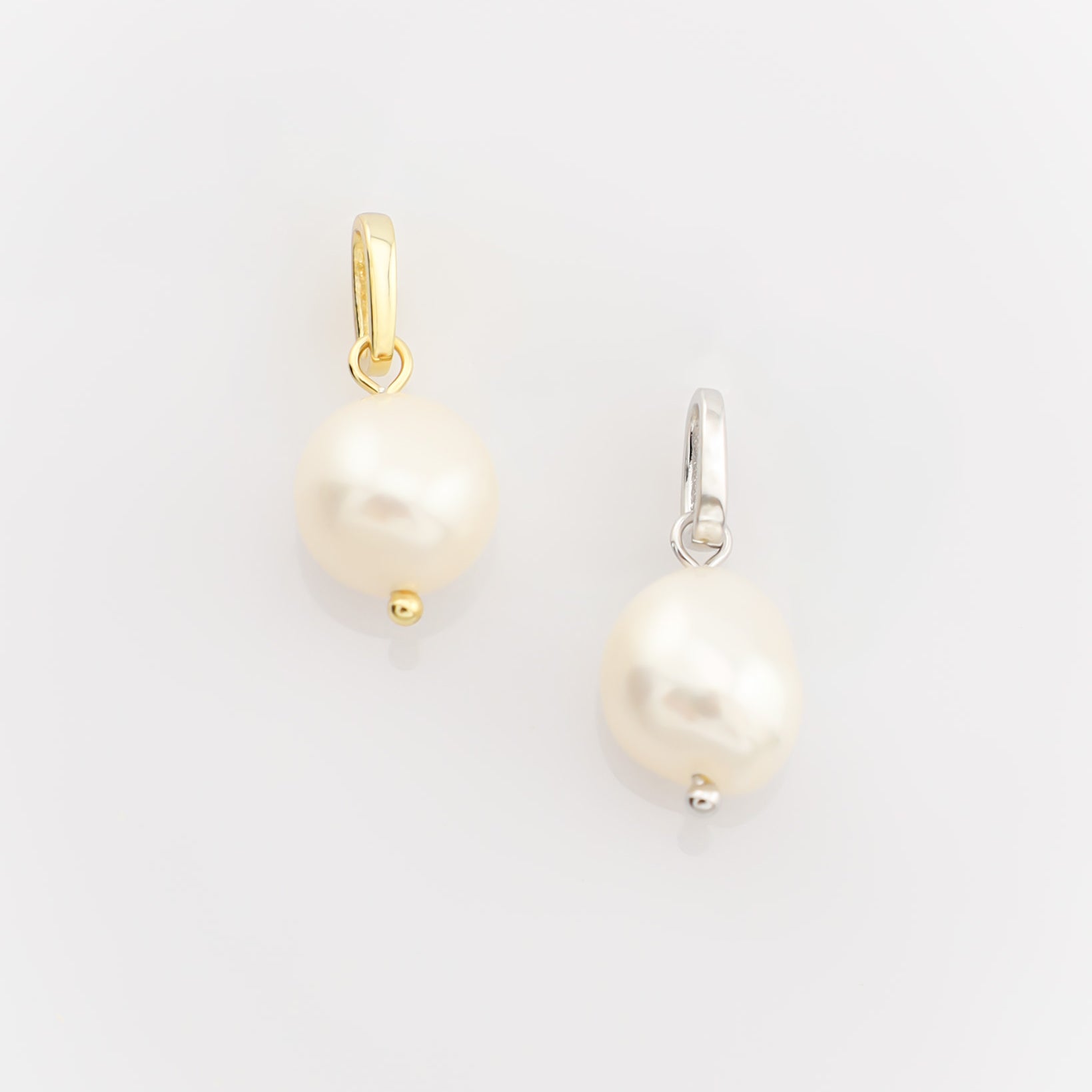 Two pearl earrings on a light gray background