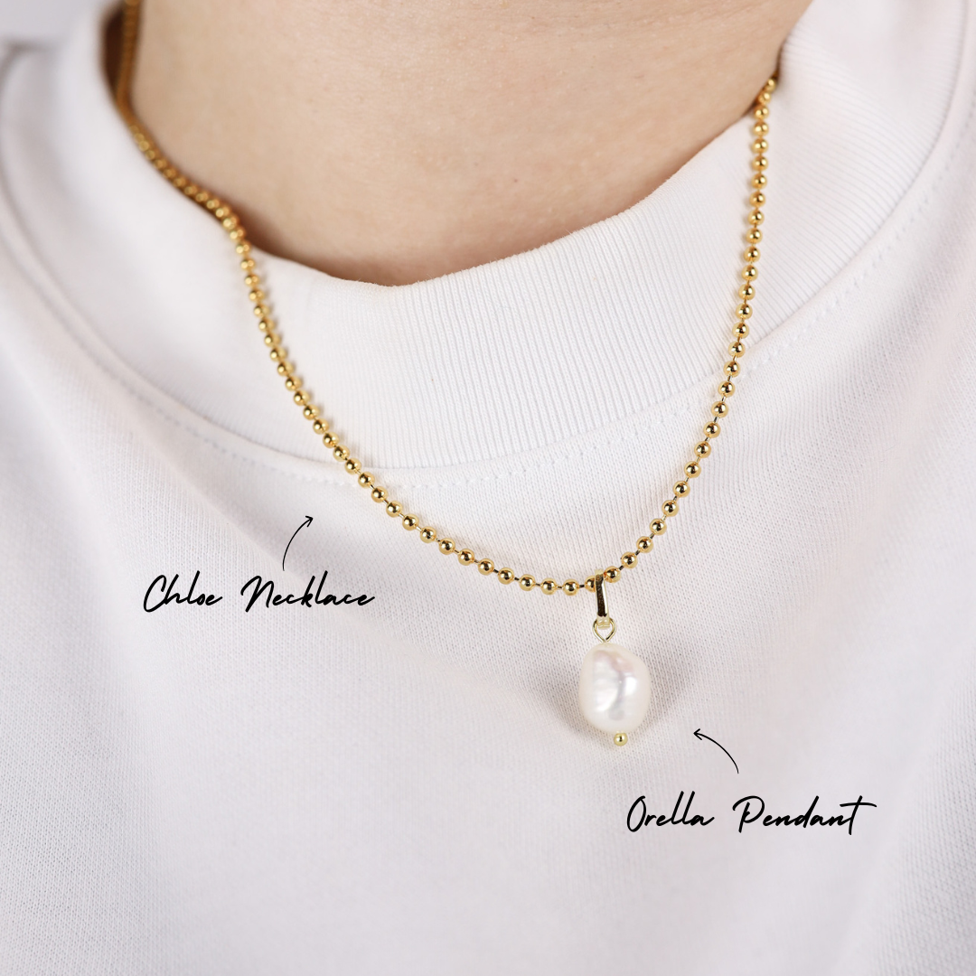 Gold necklace with a pearl pendant on a white background