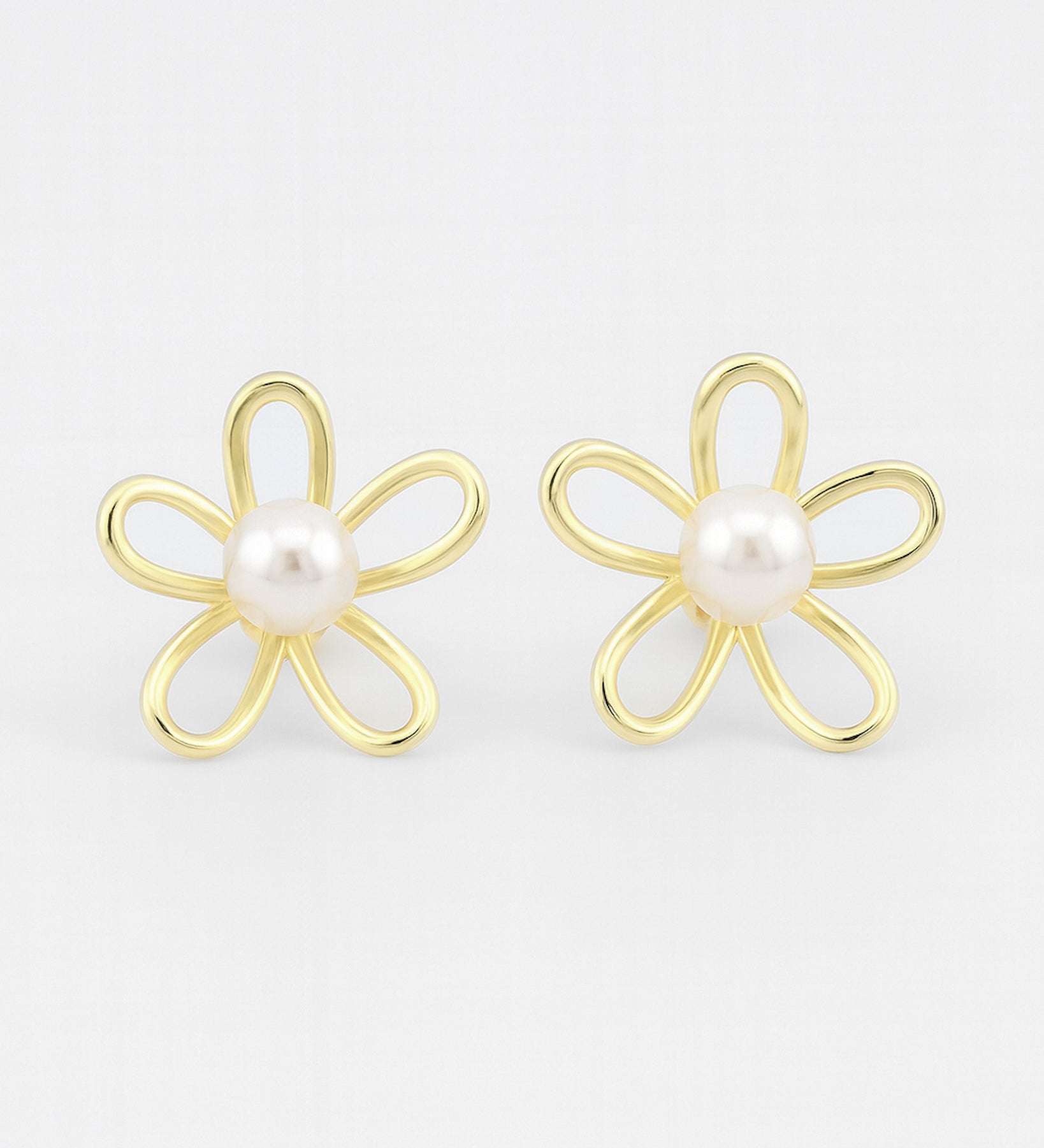 Gold flower-shaped earrings with pearl centers on a white background