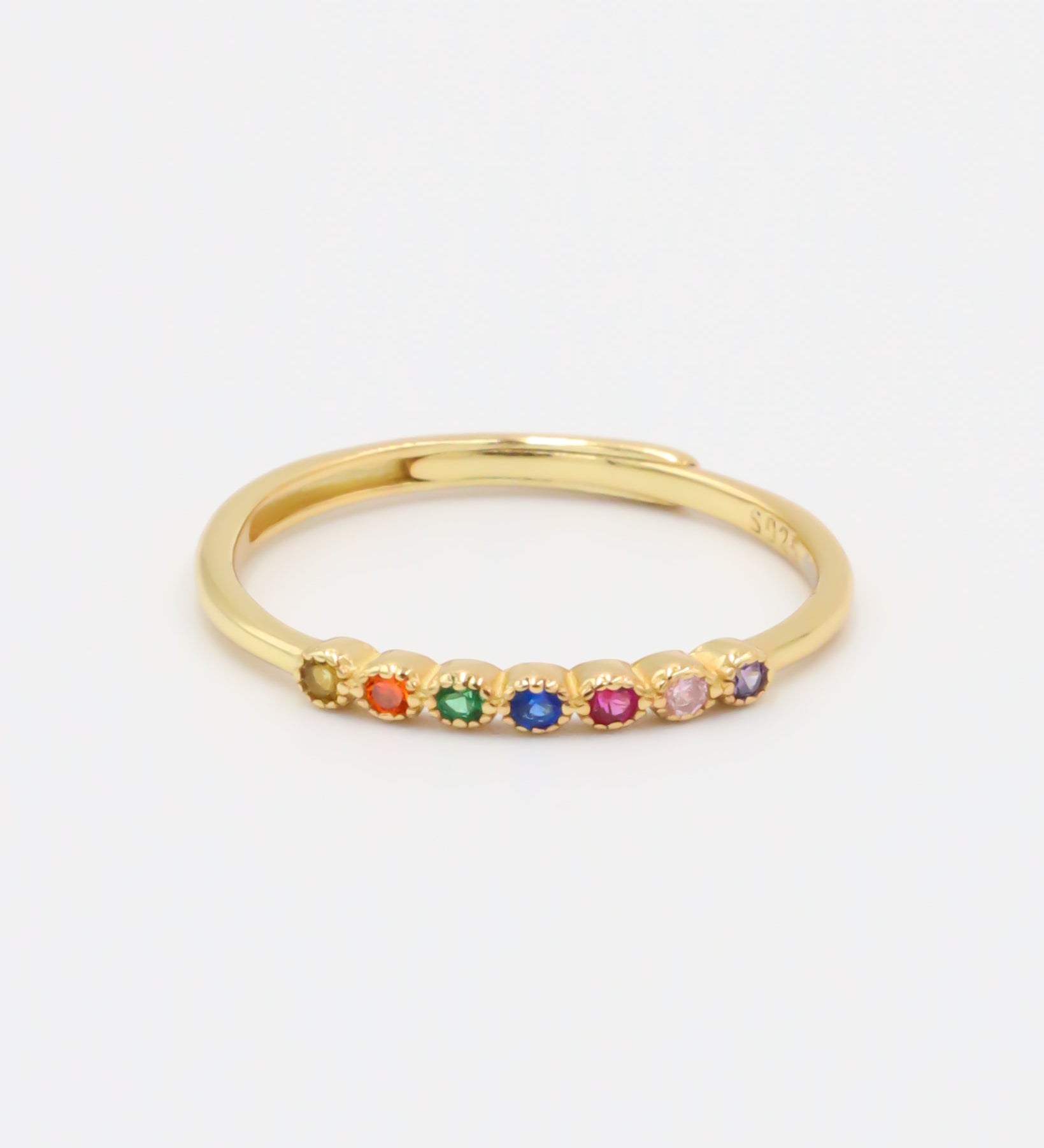 A gold-colored ring with multiple multicolored gemstones set close together.