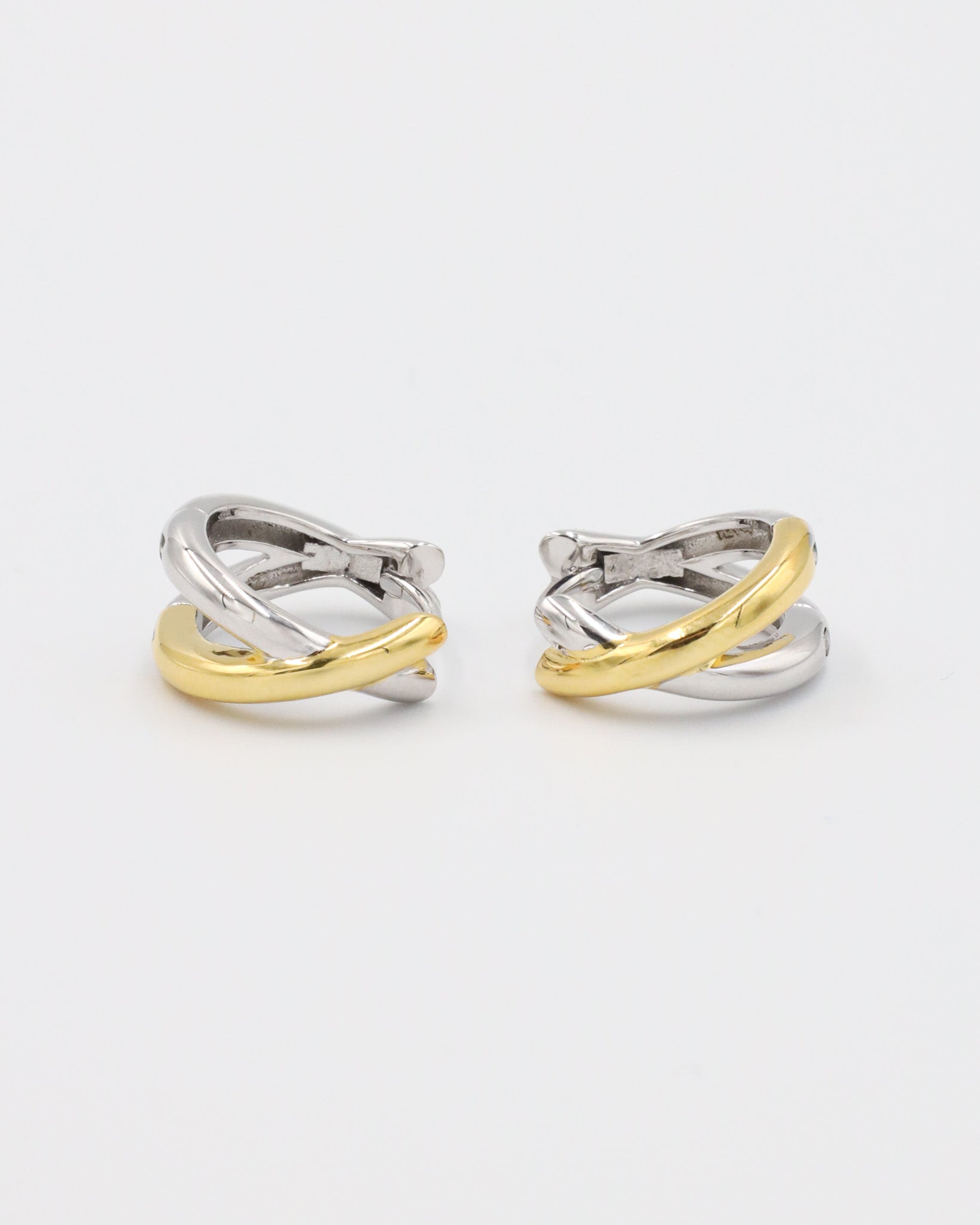 A pair of bicolor hoop earrings with a hinged clasp, featuring mixed metals design, predominantly silver with gold accents.