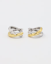 A pair of bicolor hoop earrings with a hinged clasp, featuring mixed metals design, predominantly silver with gold accents.