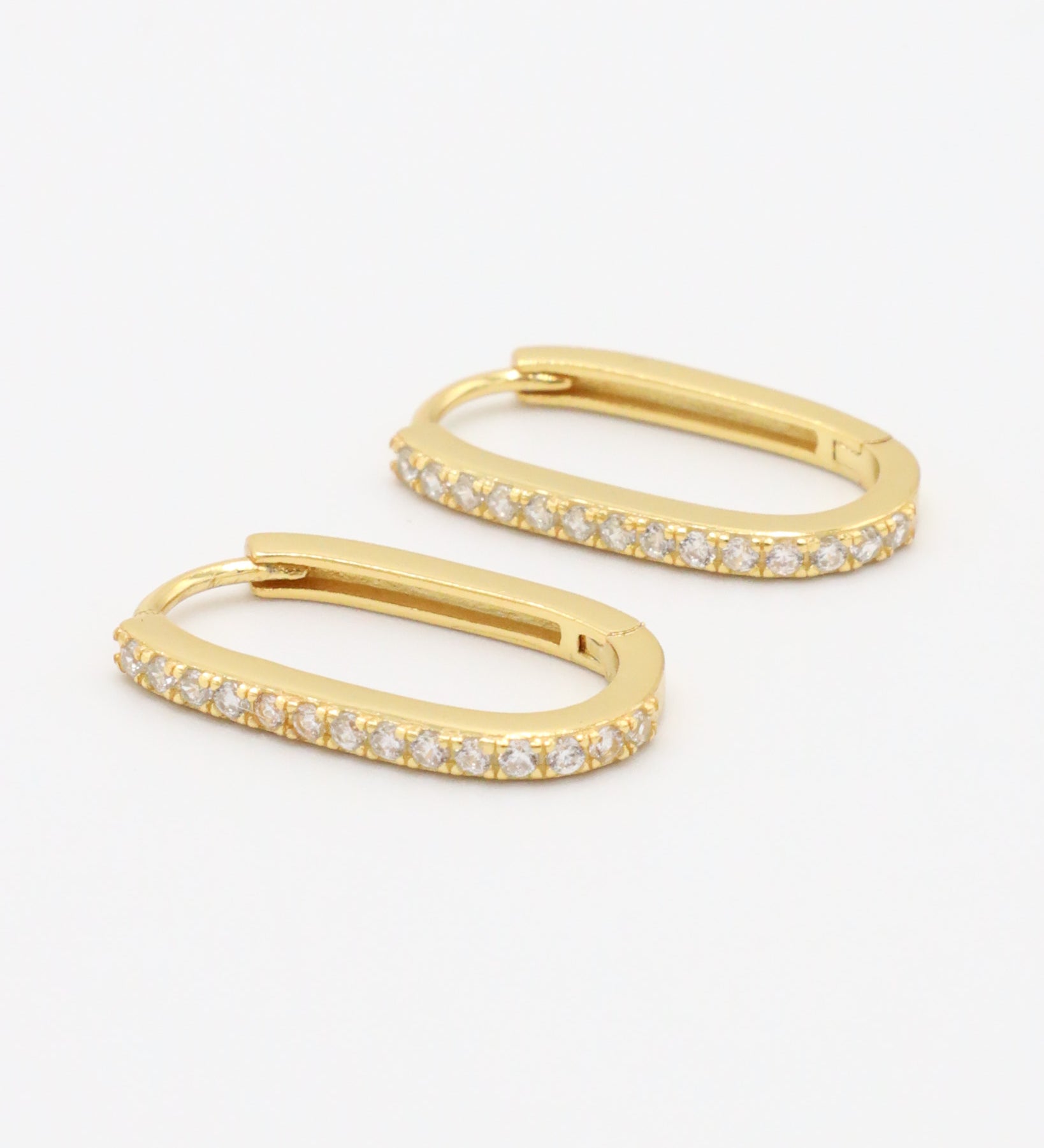 Gold colored hoop earring with a row of inset stones on the hoop, displayed against a white background.