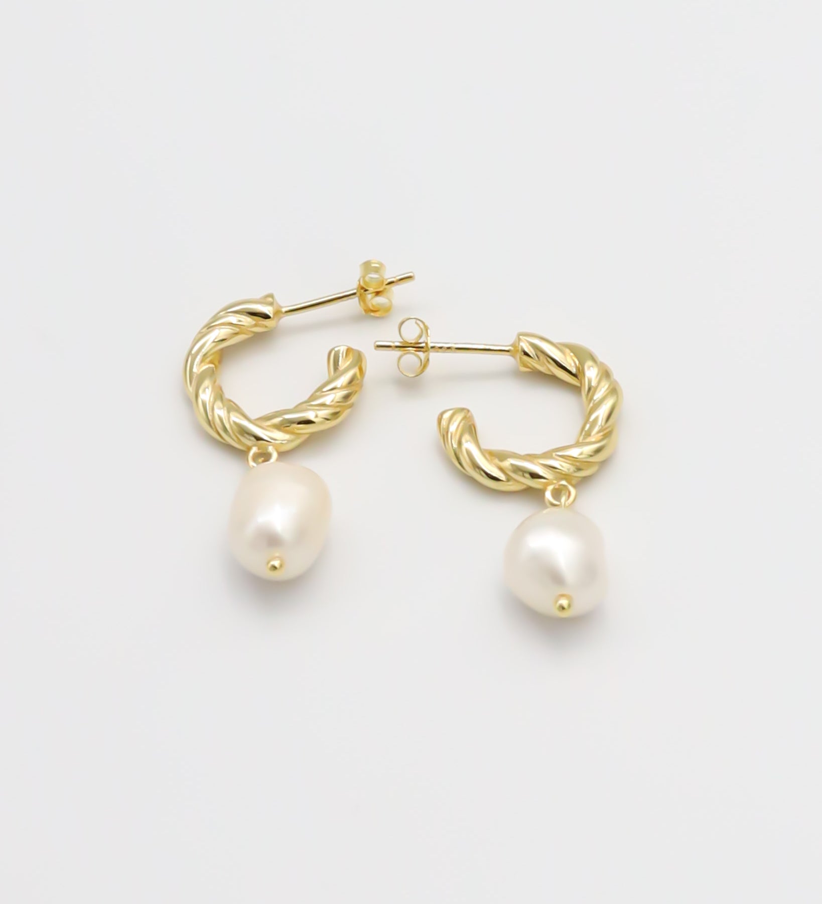 A pair of gold-colored hoop earrings with white pearl accents.