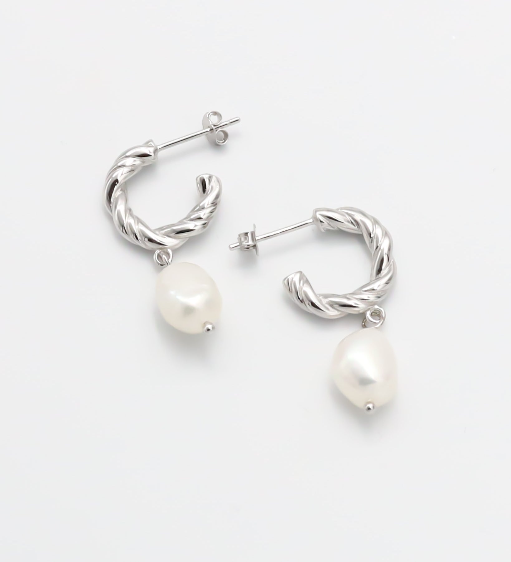 A pair of silver hoop earrings with white pearl studs.
