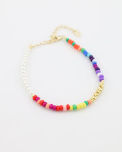 Colorful beaded bracelet with gold chain on a white background