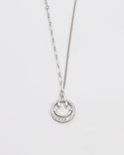 A silver necklace with a circular pendant featuring a smiley face design, displayed against a white background.