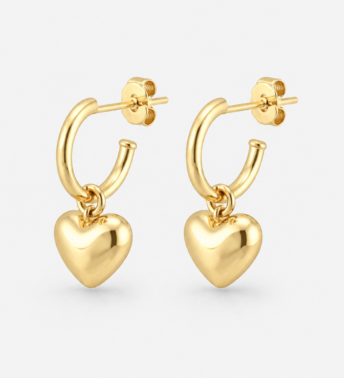 A pair of gold hoop earrings with dangling polished heart charms, shown on a light gray background.