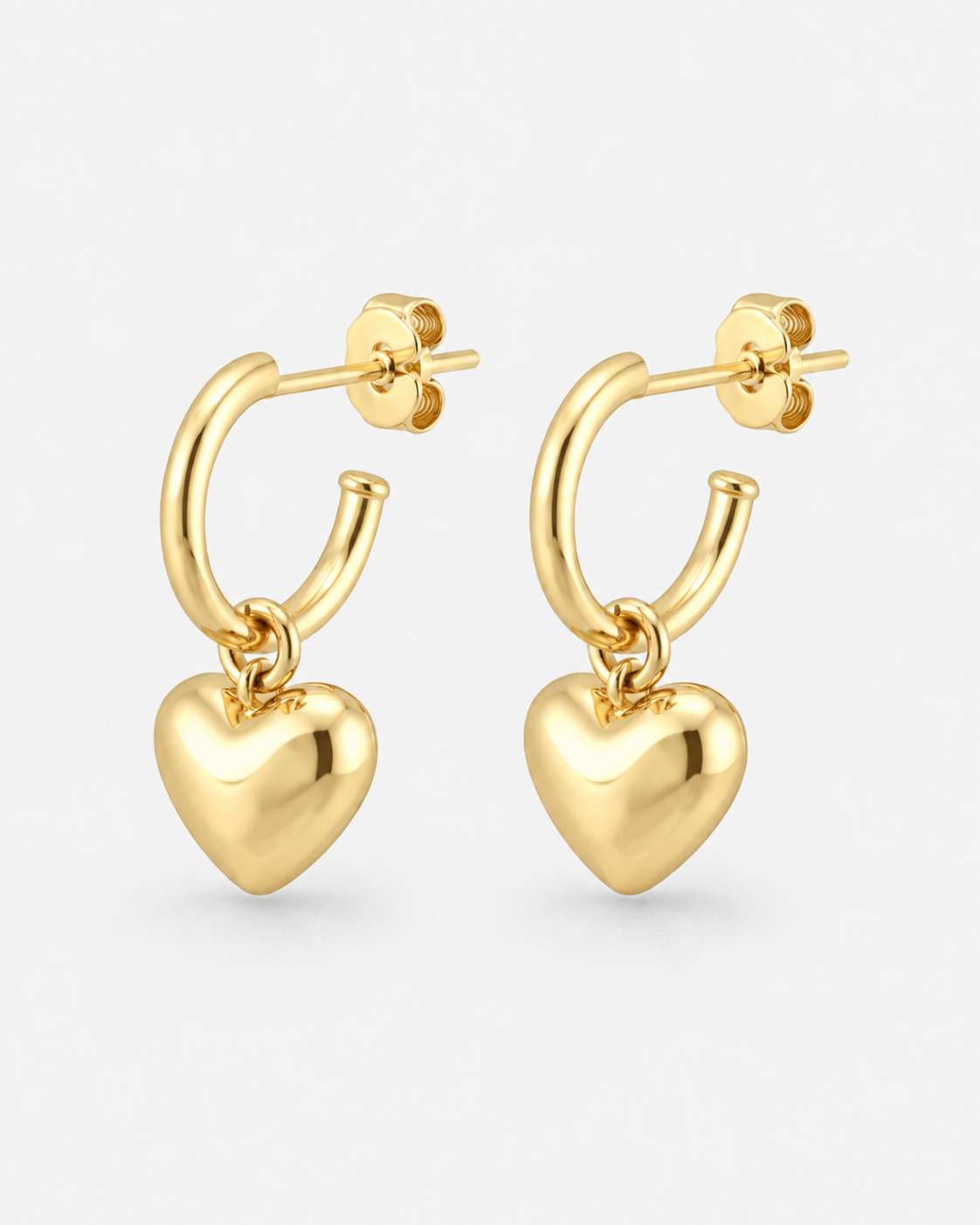 A pair of gold hoop earrings with dangling polished heart charms, shown on a light gray background.