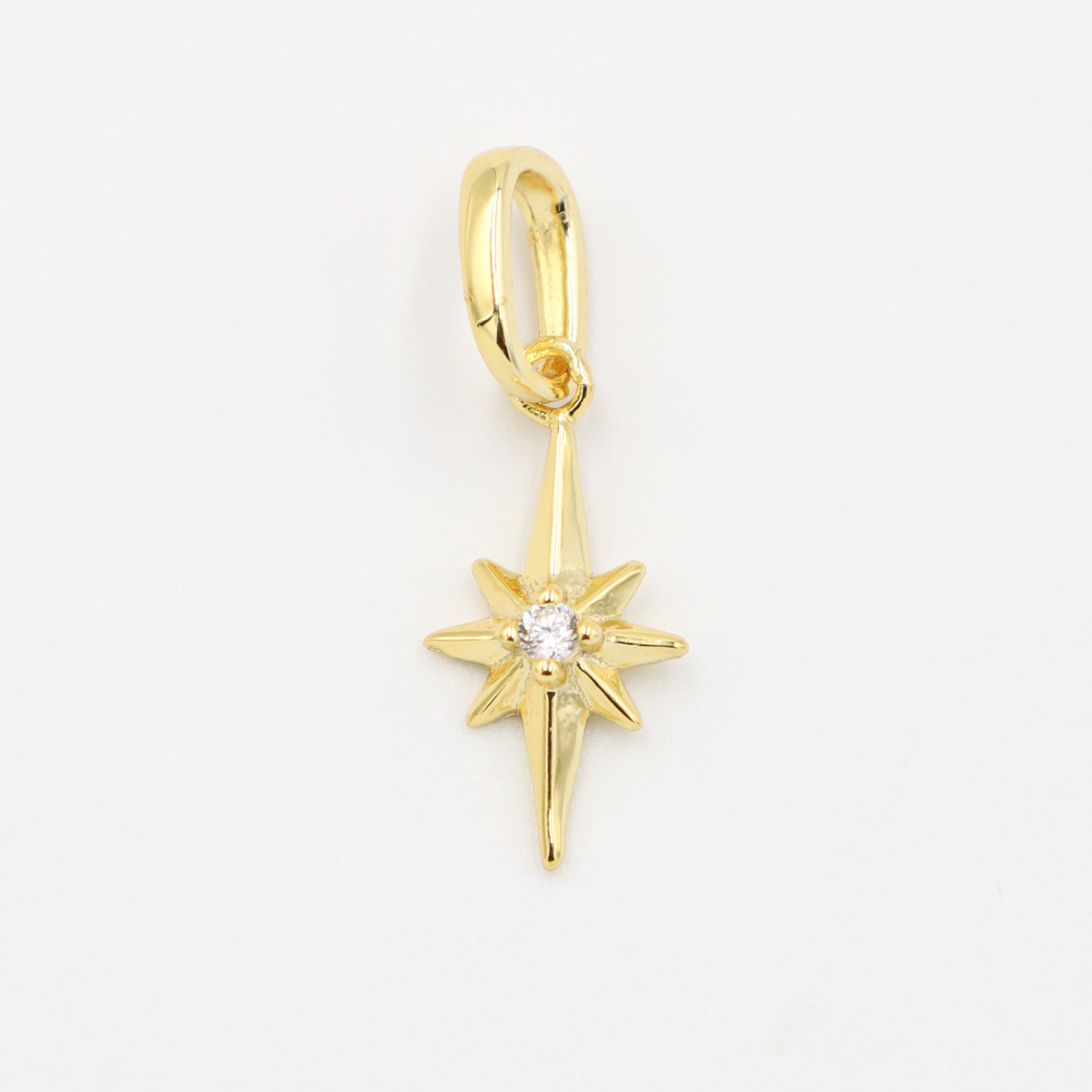 Gold star pendant with a sparkling zirconia stone on a smooth gold finish.