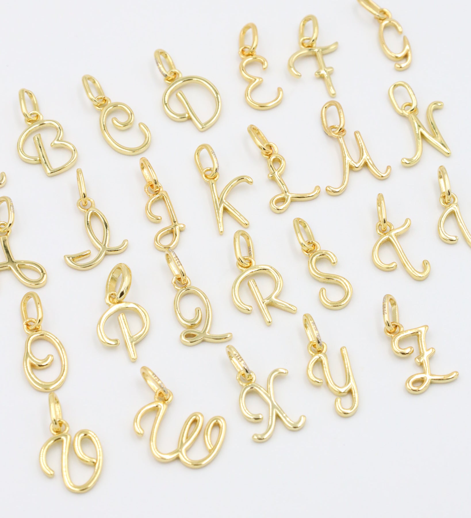 Gold-plated letter curve alphabet pendants arranged neatly for display.