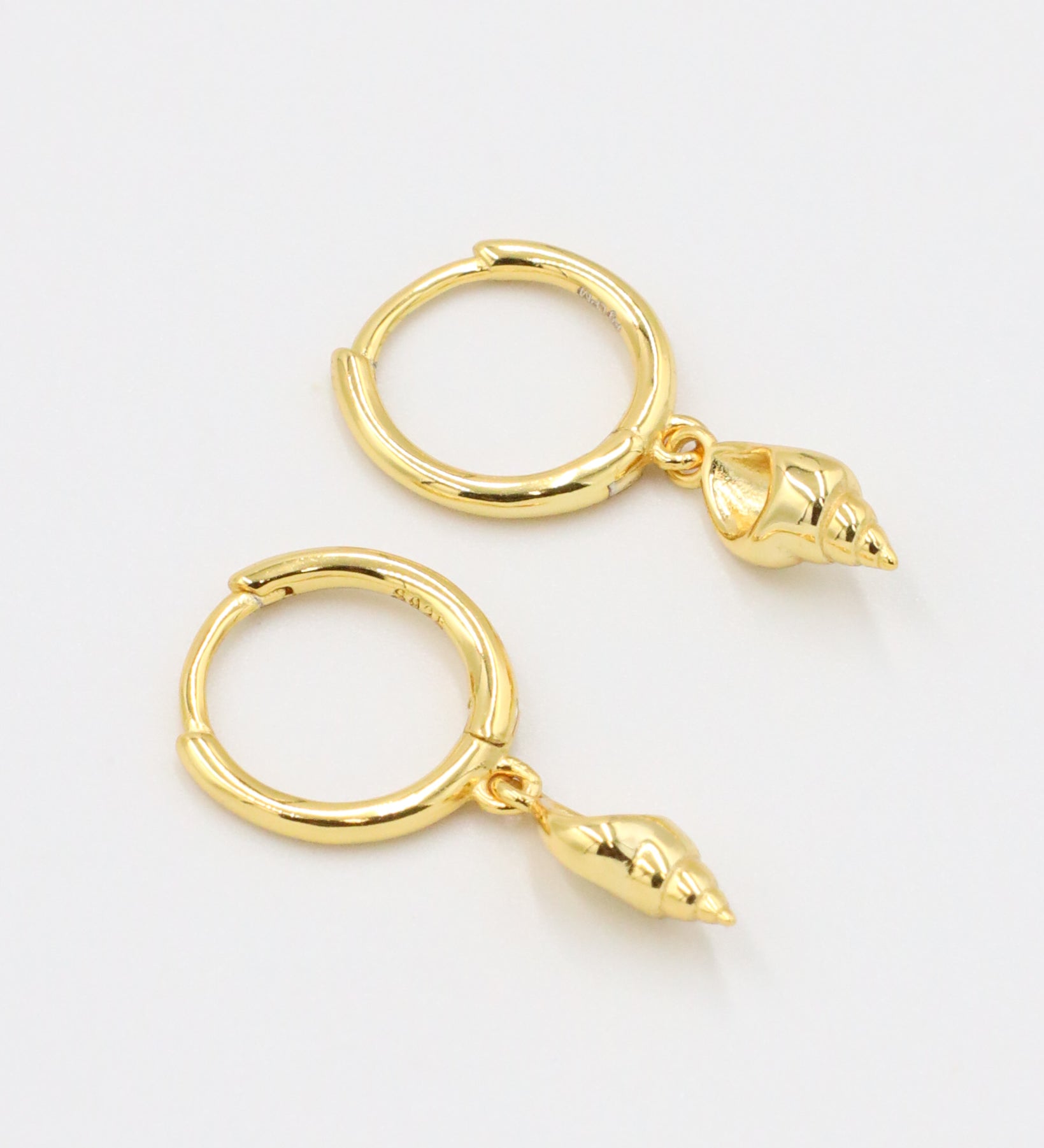 A pair of "Maddy" earrings, crafted from gold-plated 925 sterling silver, with seashell charms dangling from hoops for a beach-inspired look.