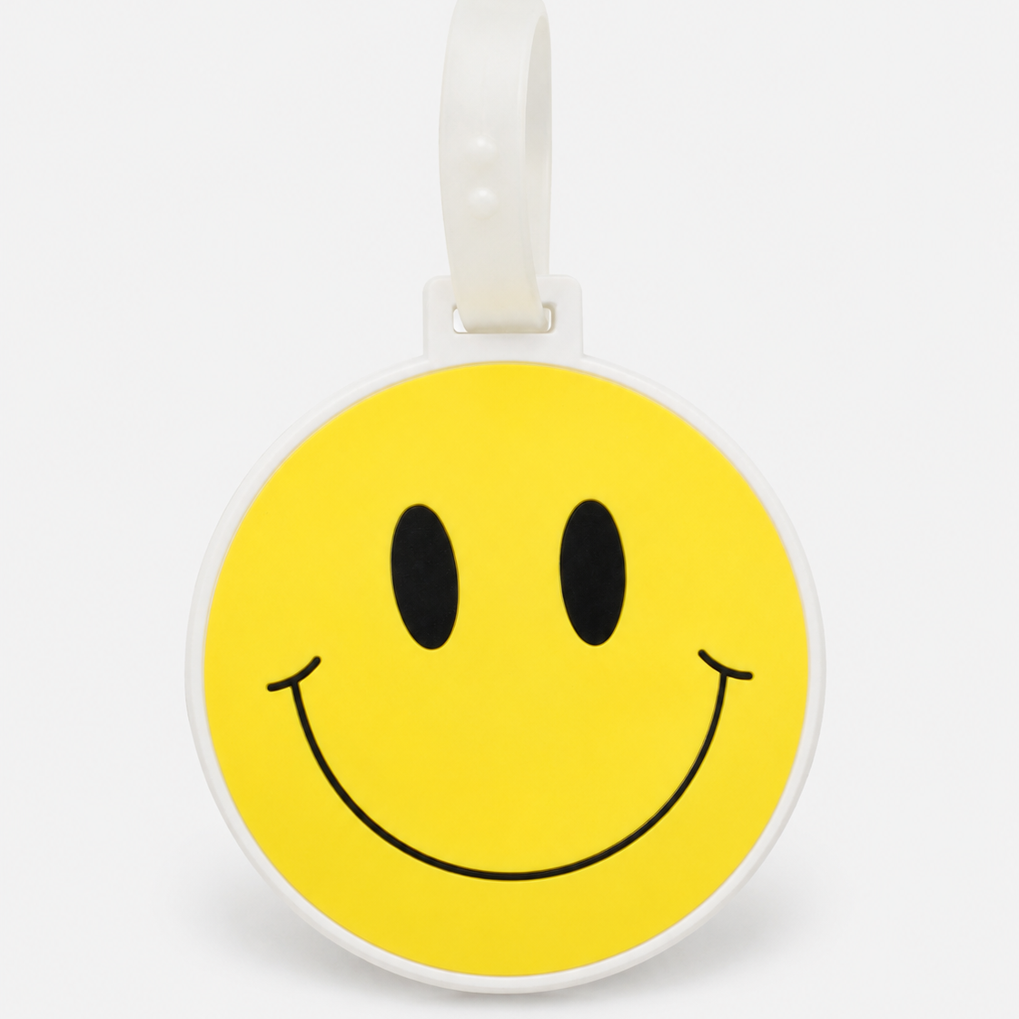 Smiley suitcase tag by ruru. studios with a yellow smiley face and white loop on a clean white background