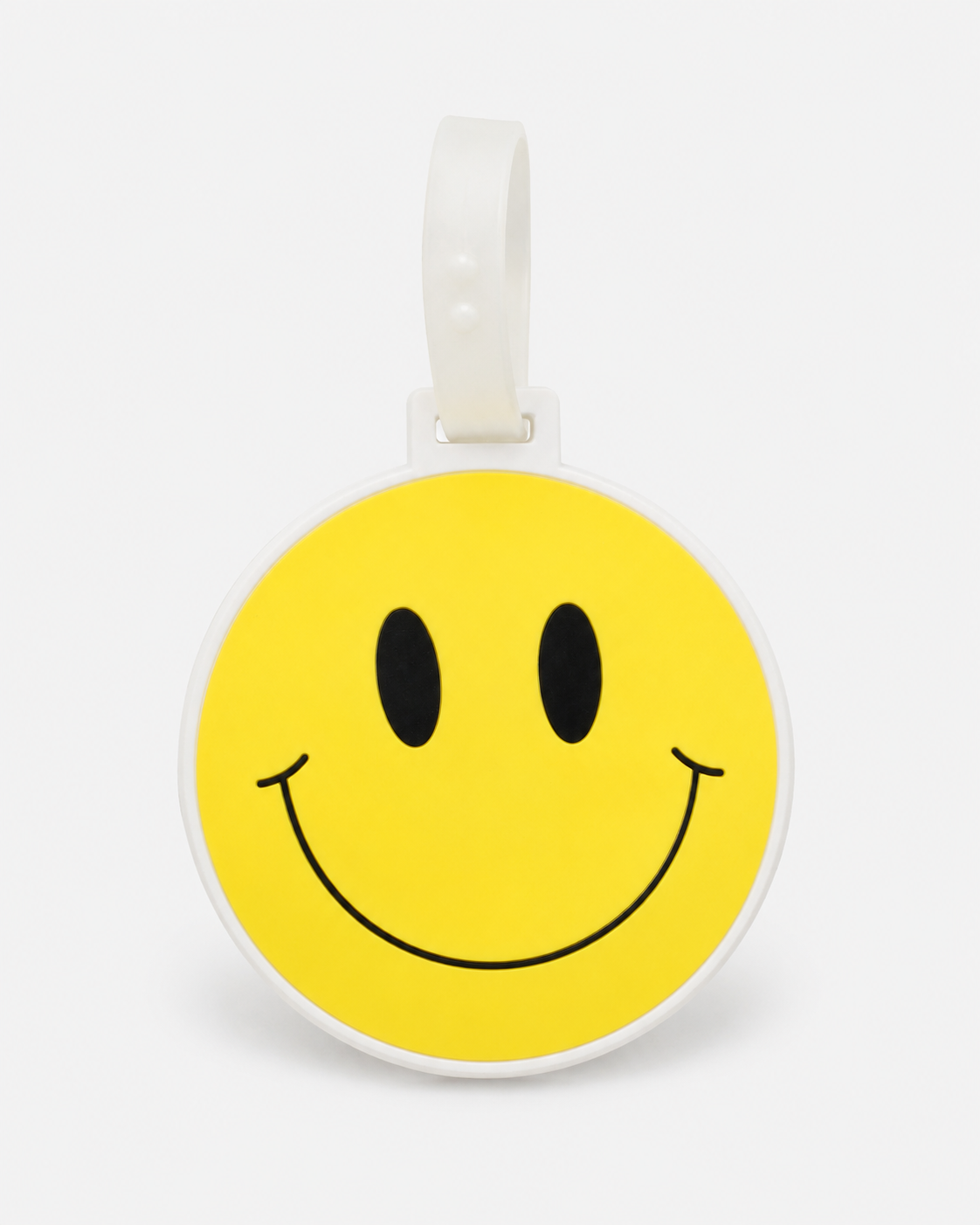 Smiley suitcase tag by ruru. studios with a yellow smiley face and white loop on a clean white background
